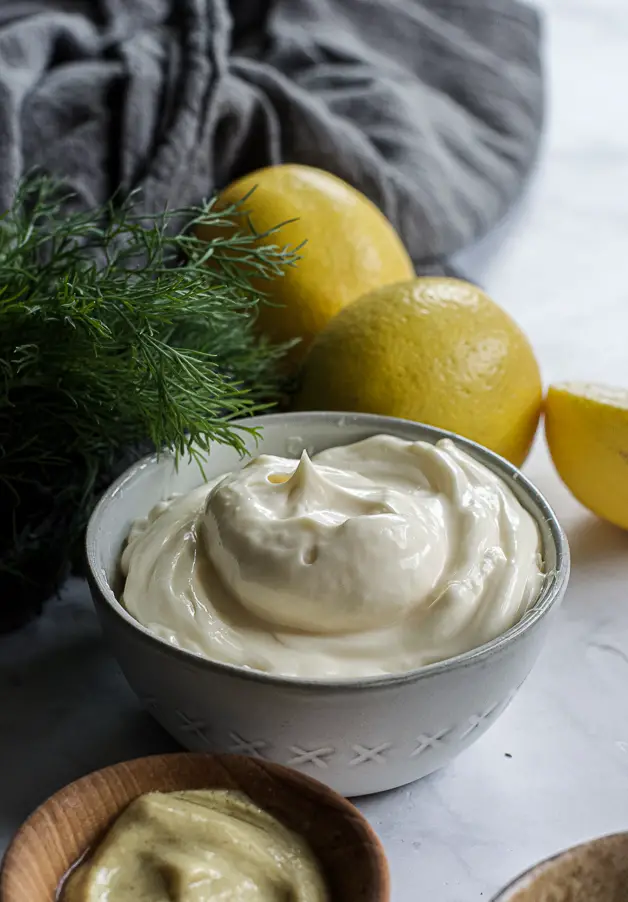 white creamy substance in a bowl with herbs and lemons