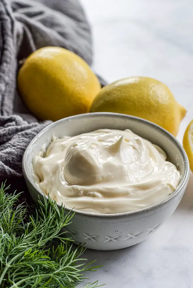 mayo in a bowl with lemons and a bunch of dill