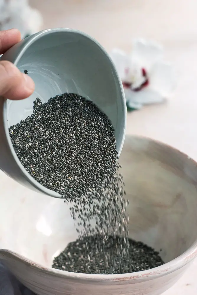 chia seeds being poured into a bowl