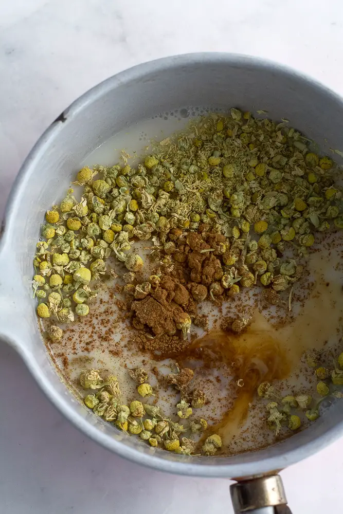 chamomile flowers in a white liquid in a small pan