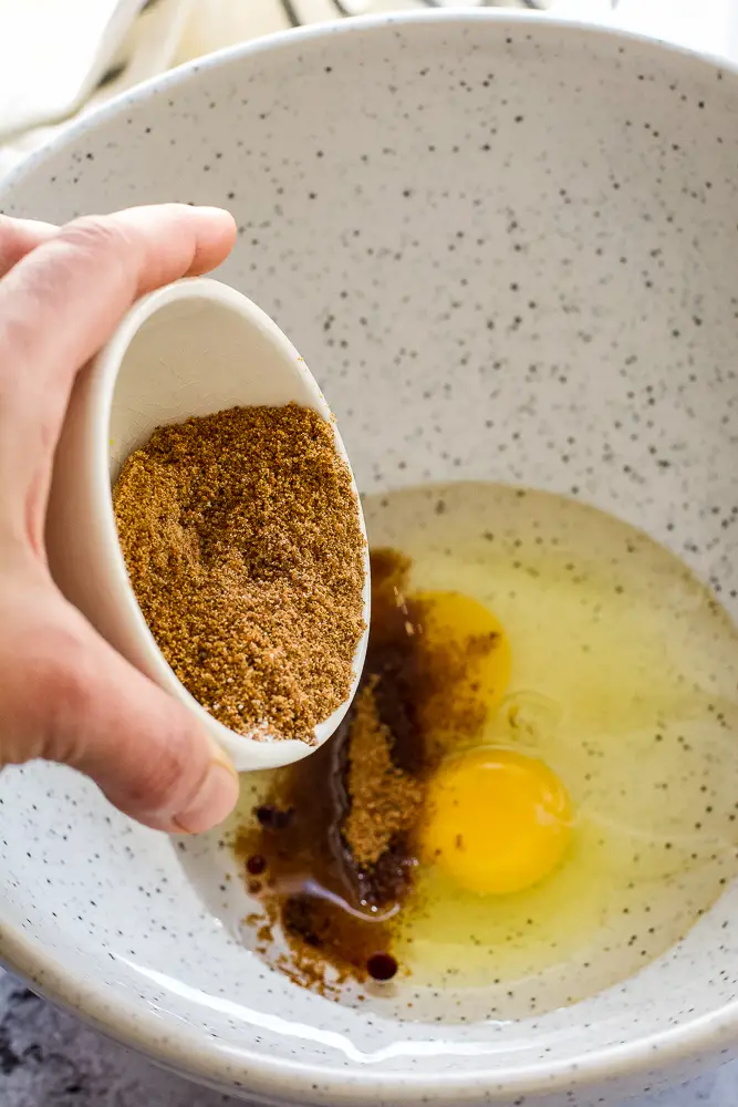 dark sugar being dropped into a bowl with eggs