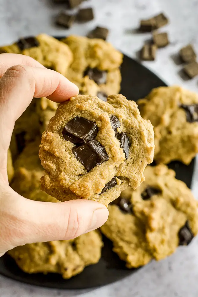 cookies on a plate with chocolate chunks and hand holding up a cookie