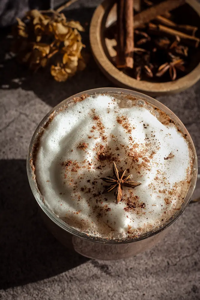 chocolate drink in a clear mug with froth on top, star anise
