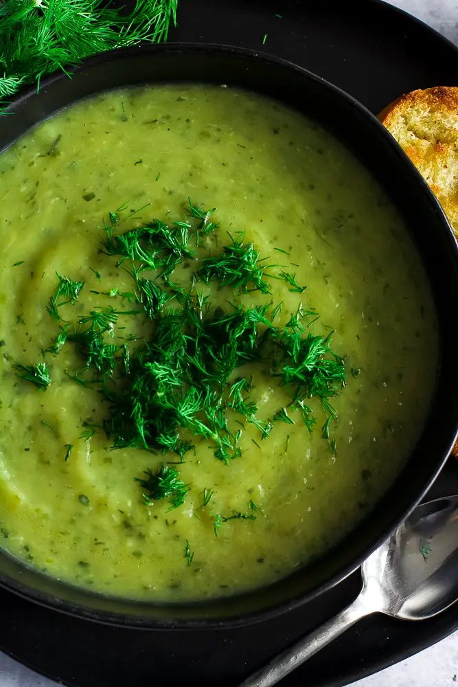 creamy green soup in a black bowl on a table