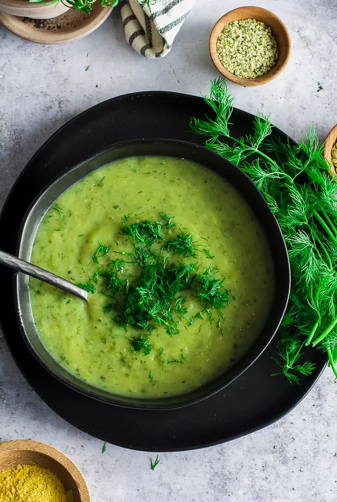 creamy green soup in a black bowl on a table