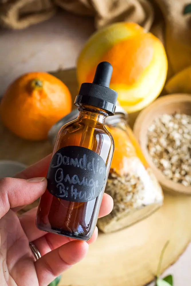 brown little bottle, cinnamon sticks, a jar filled with orange slices and chopped dried root. 