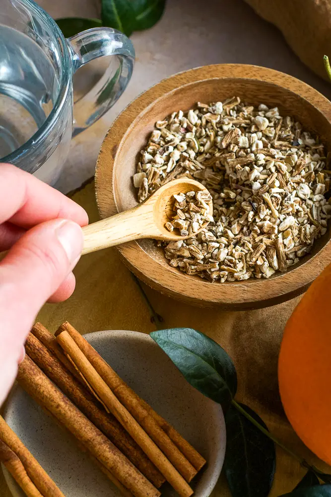 cinnamon sticks and a hand holding a spoon or chopped dried root