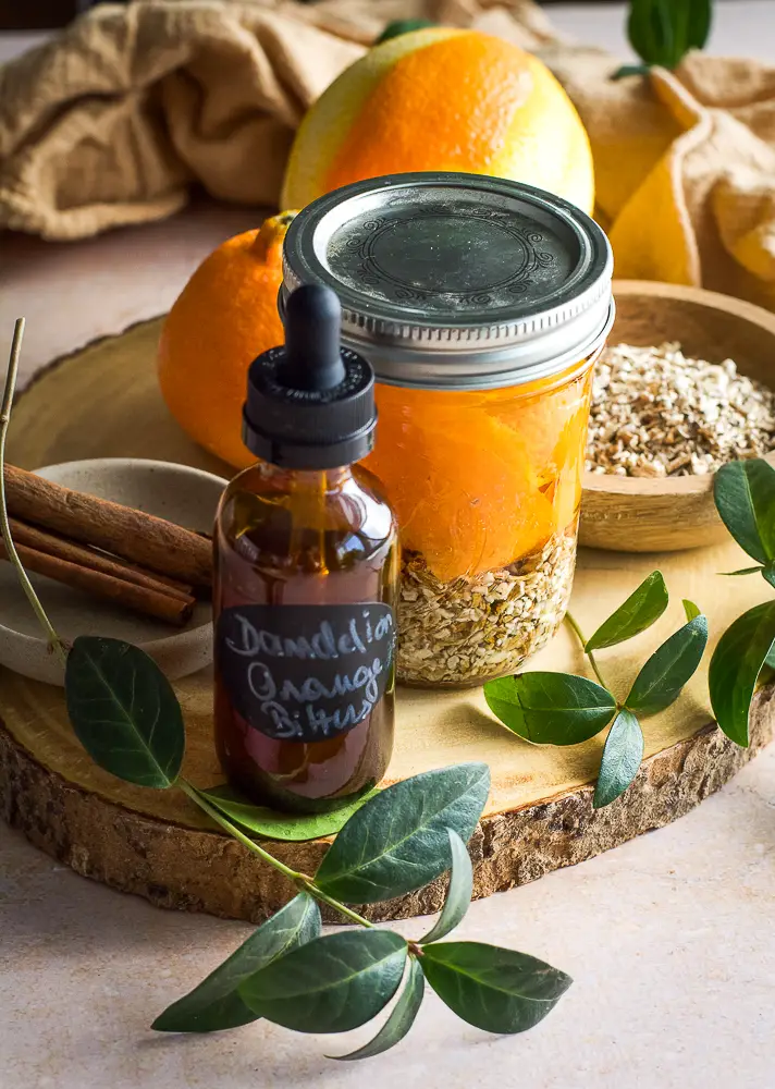 brown little bottle, cinnamon sticks, a jar filled with orange slices and chopped dried root. 
