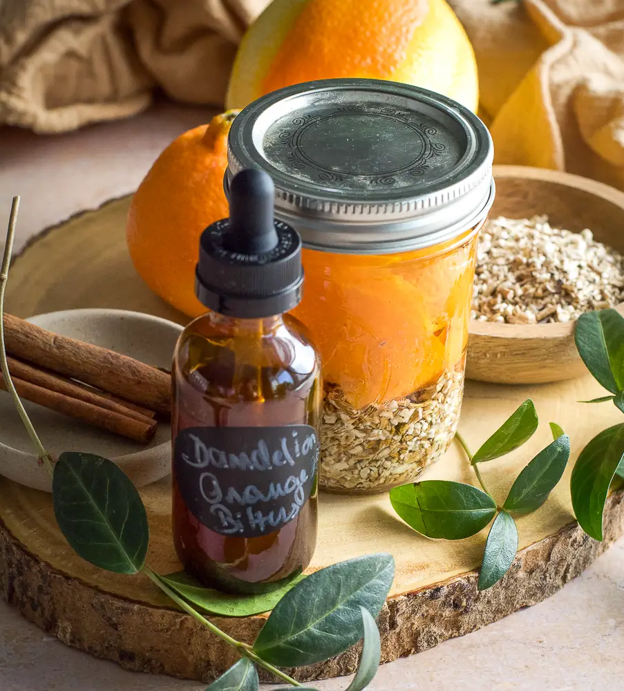 brown little bottle, cinnamon sticks, a jar filled with orange slices and chopped dried root. 