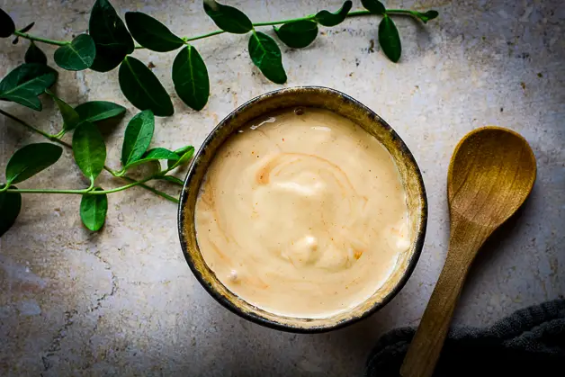 mayo with redish hint in a small bowl and a wooden spoon