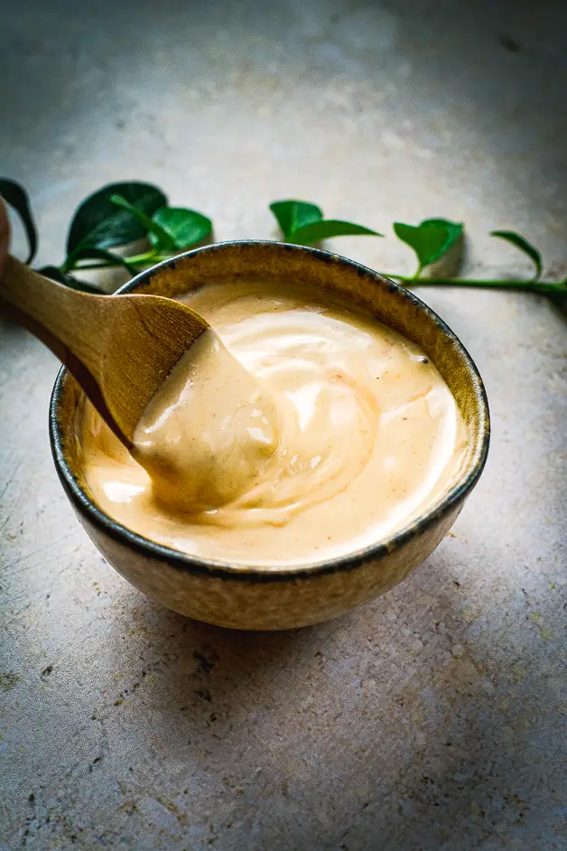 mayo with redish hint in a small bowl and a wooden spoon