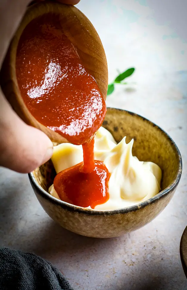 red sauce being poured into mayo sauce