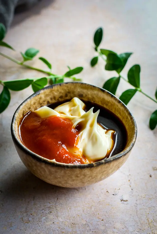 bowl with mayo, brown liquid and red liquid