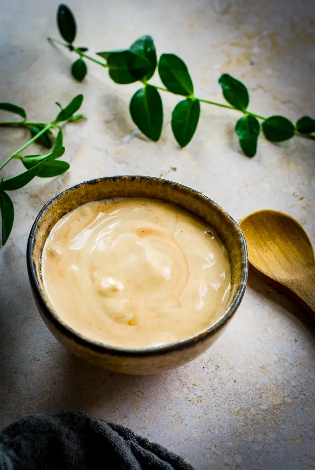 mayo with redish hint in a small bowl and a wooden spoon