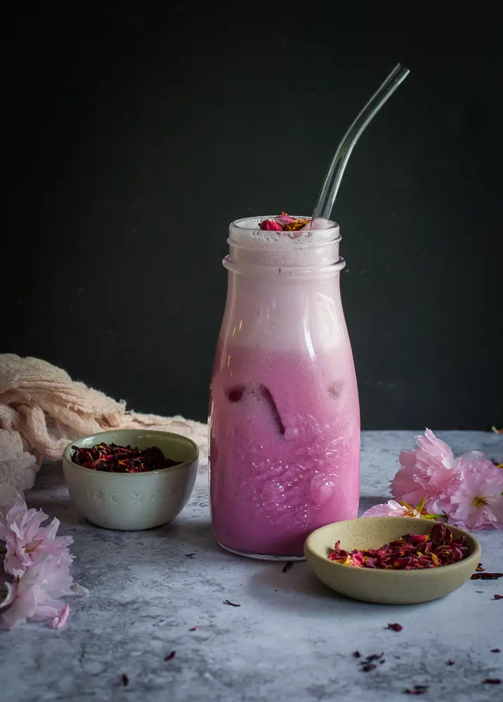 Pink drink in a glass mug with rose petals on top