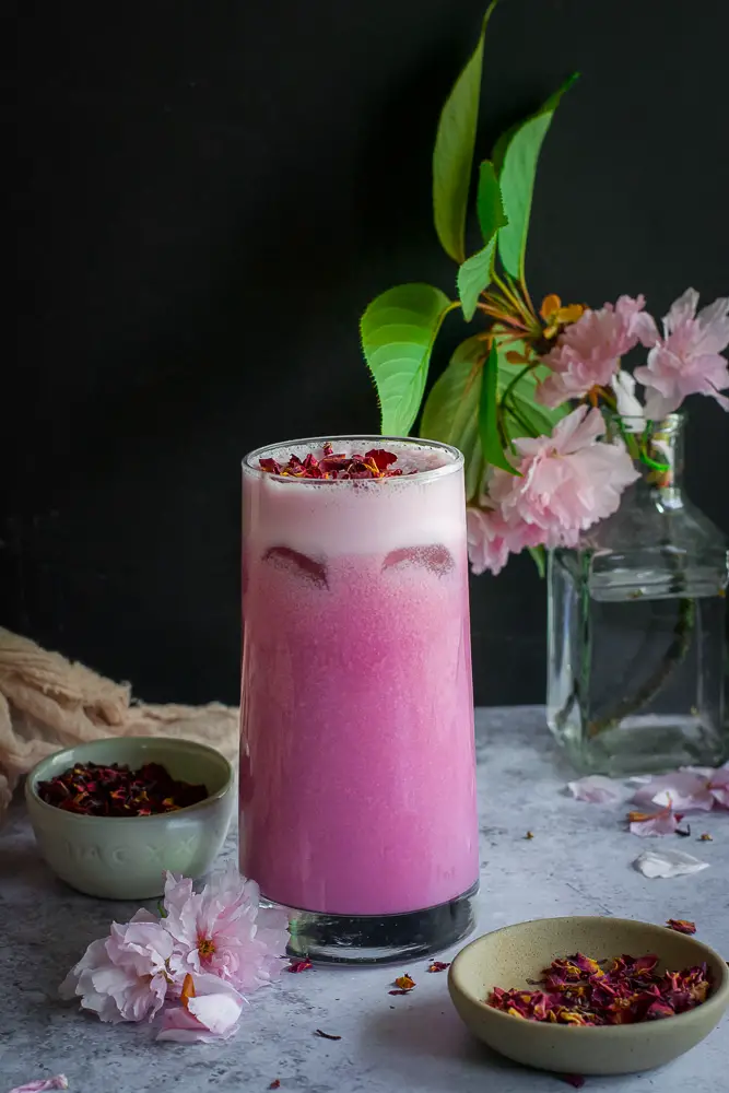 Pink drink in a glass with rose petals on top
