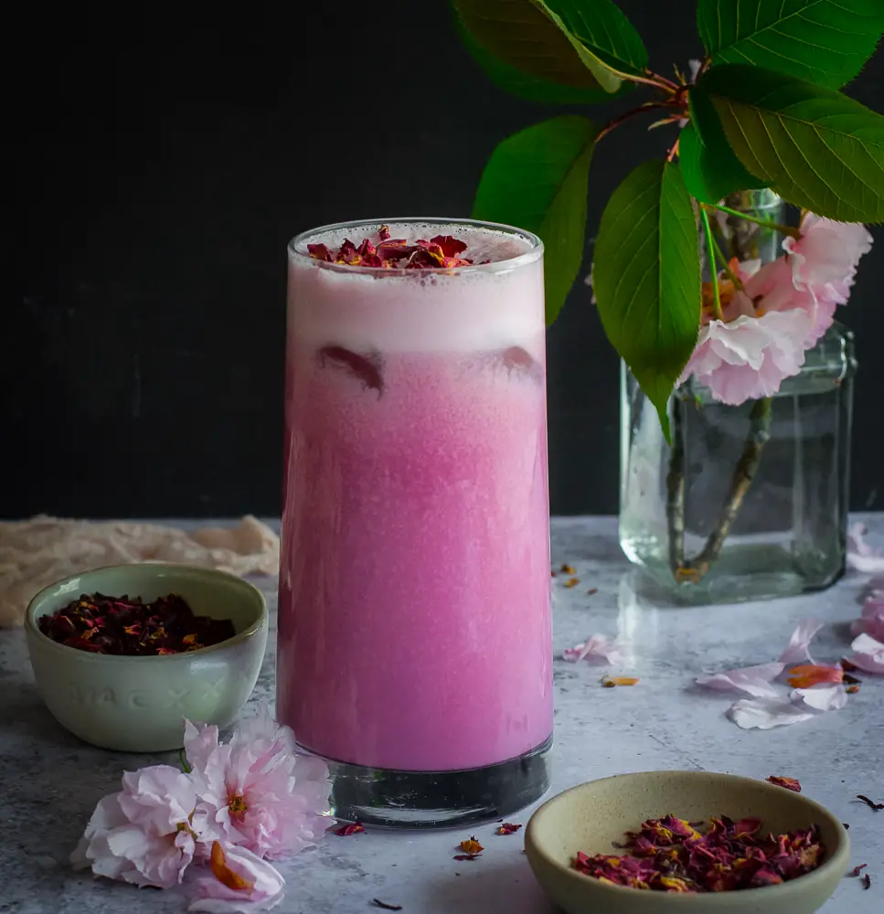 Pink drink in a glass with rose petals on top