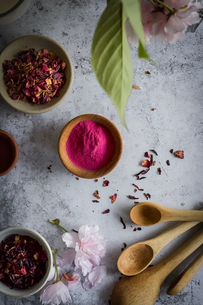 pink powder in a small bowl and red petals in other small bowls