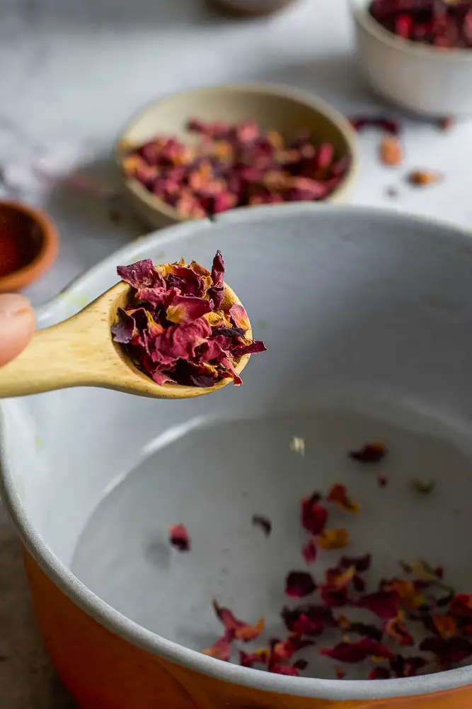red petals on a spoon being added to a pan