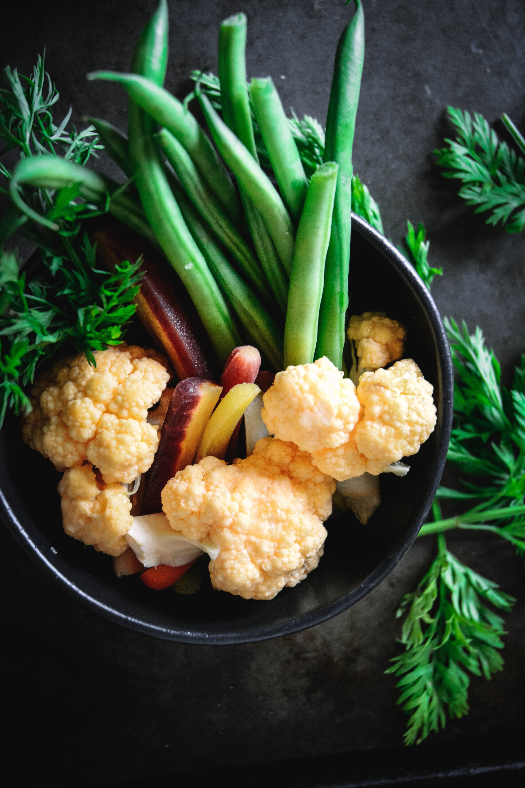 cauliflower carrots and beans in a black bowl