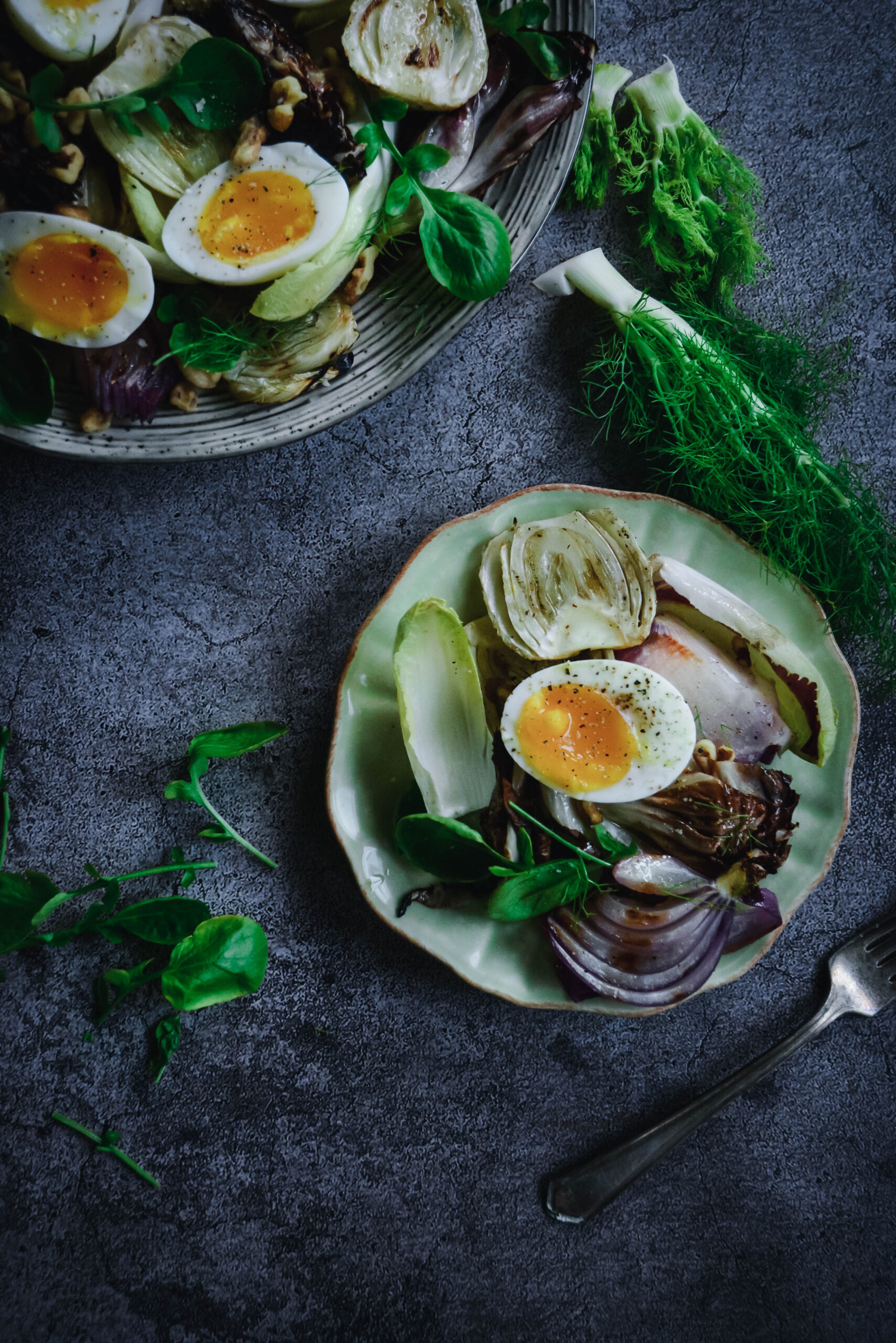 halved soft boiled eggs on greens on two plates