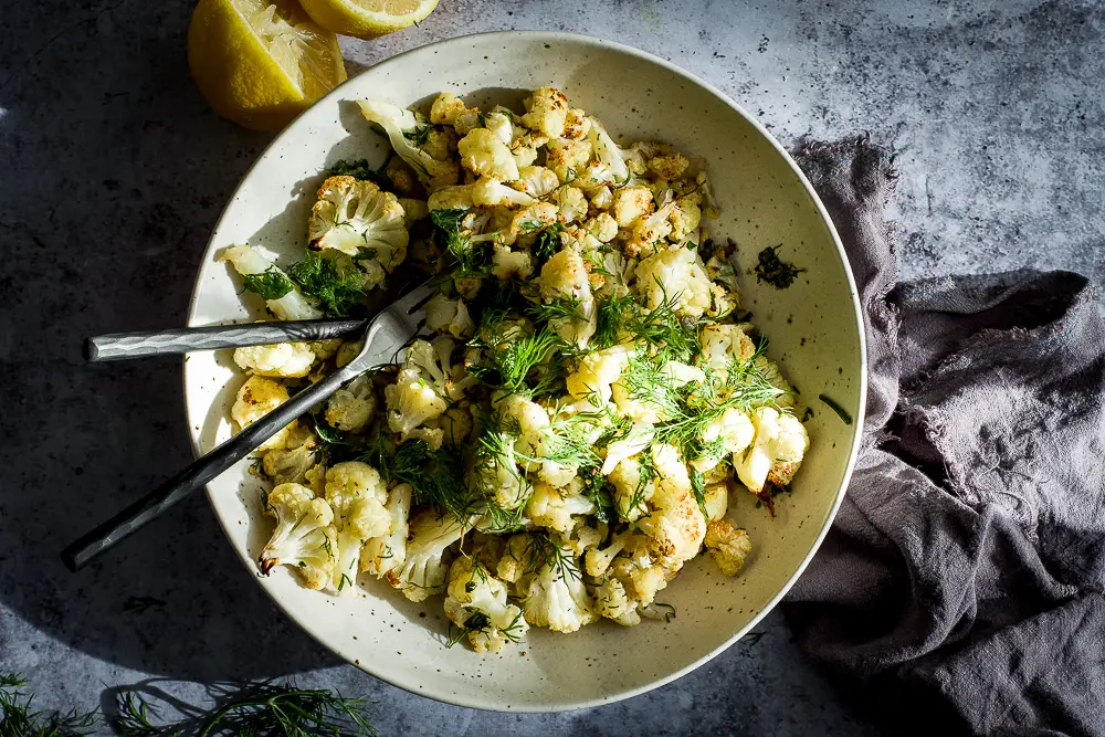 Cauliflower on a plate with herbs and fork and spoon