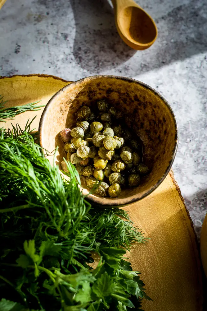 capers in a dish and herbs