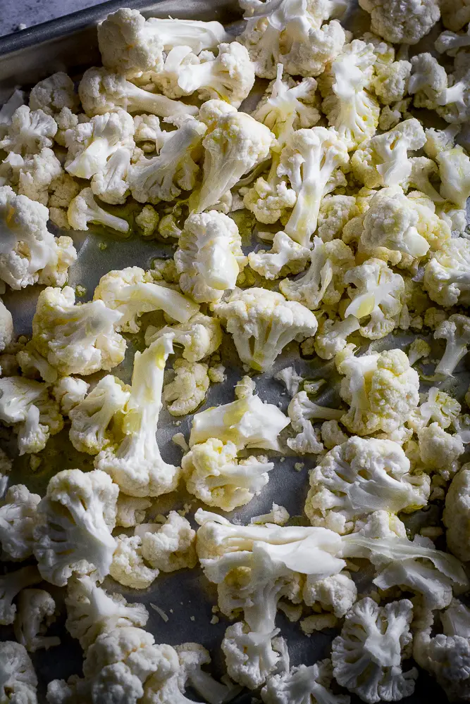 cut cauliflower on a roasting tray with olive oil